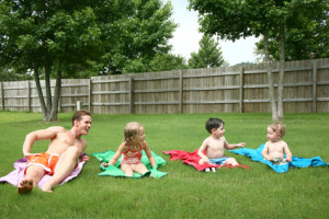 Children on towels with dad in the backyard